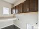 Neutral laundry room featuring dark wood cabinets and a folding counter at 21295 E 61St Dr, Aurora, CO 80019