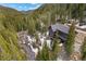 Aerial view of gray home nestled in a forest with a creek running nearby at 379 Rainbow Rd, Idaho Springs, CO 80452