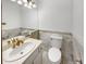 Small bathroom with a white vanity, matching toilet and beautiful tile wainscoting at 1394 E Panama Dr, Centennial, CO 80121