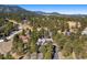 Overhead view of home surrounded by dense trees and snow-dusted landscape with mountain view in the background at 2851 Interlocken Dr, Evergreen, CO 80439