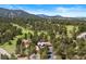 Stunning aerial view of mountain home nestled among mature trees and adjacent to a golf course at 2851 Interlocken Dr, Evergreen, CO 80439