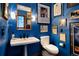 Stylish bathroom with bright blue walls, pedestal sink, toilet, and decorative framed artwork at 2851 Interlocken Dr, Evergreen, CO 80439