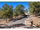 Charming home with a rustic exterior, mature trees, and a paved driveway leading to an attached garage at 2851 Interlocken Dr, Evergreen, CO 80439