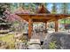 Secluded gazebo with seating, rock landscaping, water feature, and mature trees at 2851 Interlocken Dr, Evergreen, CO 80439