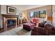 Cozy living room with a classic fireplace, comfortable seating, and a large window offering scenic views at 2851 Interlocken Dr, Evergreen, CO 80439