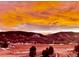 Vibrant sunset sky over a serene landscape with hills and trees, creating a beautiful backdrop at 4502 Echo Cliff Ln, Larkspur, CO 80118