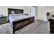 Spacious bedroom with gray carpet, a large wooden bed frame, and white closet doors at 7433 Ellingwood Cir, Frederick, CO 80504