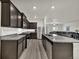 Bright kitchen showcasing wood-look flooring, dark cabinetry, stainless steel appliances, and a granite-topped center island at 7433 Ellingwood Cir, Frederick, CO 80504
