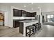 Open kitchen featuring dark cabinetry, a stainless steel refrigerator, a tiled backsplash, an island and modern stool seating at 7433 Ellingwood Cir, Frederick, CO 80504
