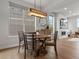 Bright dining room with a round wood table, modern light fixture, and large windows at 9378 E 60Th Pl, Denver, CO 80238