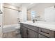 Well-lit bathroom featuring modern fixtures, gray cabinetry, and tiled shower-tub combination at 8903 Springsong Ln, Littleton, CO 80125