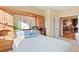 Sunlit bedroom showing the bed and built-in wooden cabinetry; open doorway reveals the kitchen and breakfast bar at 8796 E 150Th Ct, Thornton, CO 80602