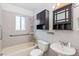 Cozy bathroom featuring tiled walls, a bathtub with shower, toilet, sink and dark wooden medicine cabinet, ideal for relaxation at 1680 S Patton Ct, Denver, CO 80219