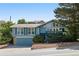 Charming exterior of a light-blue home featuring a well-maintained front yard and an attached garage at 310 S Alkire St, Lakewood, CO 80228