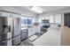 Bright kitchen featuring stainless steel appliances, white cabinetry, and a view of the neighborhood at 12069 Monaco Ct, Brighton, CO 80602