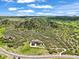 Expansive aerial view showcasing a large stone house nestled in a lush green landscape with rolling hills at 4222 Serenade Rd, Castle Rock, CO 80104