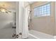 Bathroom featuring a tub with shower, glass block window, and partial view of a cozy bedroom at 4222 Serenade Rd, Castle Rock, CO 80104