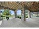 Covered patio with stone columns and arched openings, featuring hanging swings and a view of the lush landscape at 4222 Serenade Rd, Castle Rock, CO 80104
