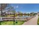 Community pond view with white fencing, mature trees, and blue sky at 23 Carla Way, Broomfield, CO 80020