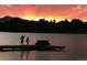 Scenic sunset view of people on a dock by a lake with a vibrant sky and mountain silhouettes at 4700 Homestead St, Bow Mar, CO 80123