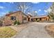 Charming exterior of home featuring a combination of stone and wood, complemented by a winding driveway and mature trees at 4700 Homestead St, Bow Mar, CO 80123