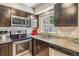 Modern kitchen features stainless steel appliances, granite countertops, and dark wood cabinets at 12059 E Hoye Dr, Aurora, CO 80012