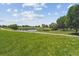 Expansive open green space with pond, walking paths, mature trees, and distant building at 12059 E Hoye Dr, Aurora, CO 80012
