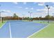 Well-maintained blue and green tennis courts with net, fencing, lights, and covered benches at 12059 E Hoye Dr, Aurora, CO 80012