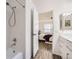 Bathroom with tiled shower-tub combination, with the view into the bedroom showcasing the bed and window at 5873 Ceylon St # E, Denver, CO 80249