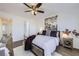 Bright bedroom featuring a ceiling fan, a window, a bed, and a view of the bathroom through the open door at 5873 Ceylon St # E, Denver, CO 80249
