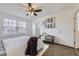 Bedroom with a ceiling fan, a window, a bed, a white door, and a small loveseat with decorative pillows at 5873 Ceylon St # E, Denver, CO 80249