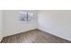Empty bedroom showcasing wood-look flooring, a window with blinds, and electrical outlets along the walls at 5873 Ceylon St # E, Denver, CO 80249