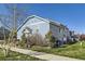Exterior view of the light blue townhouse featuring mature landscaping and sidewalk at 5873 Ceylon St # E, Denver, CO 80249