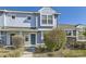 Front exterior of light blue townhouse with stone accents, well-maintained landscaping and a front door at 5873 Ceylon St # E, Denver, CO 80249