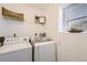 Bright laundry area featuring white washer and dryer with decorative shelves and a window with natural light at 5873 Ceylon St # E, Denver, CO 80249