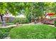 Spacious backyard features a manicured lawn, mature trees, and a charming stone patio with a wooden deck at 6112 Alkire Ct, Arvada, CO 80004
