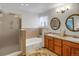 Bathroom featuring double sink vanity, decorative mirrors, and shower with glass door at 6112 Alkire Ct, Arvada, CO 80004