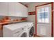 Bright laundry room with storage cabinets, shelving, and exterior door at 6112 Alkire Ct, Arvada, CO 80004