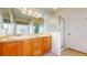 Bright bathroom with double sinks, wood cabinetry, shower stall with glass enclosure and tile flooring at 2238 Calais Dr # B, Longmont, CO 80504