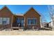 Close up of home's exterior featuring stone accents, neutral paint, a small deck, and a well-maintained lawn at 2238 Calais Dr # B, Longmont, CO 80504