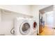 Well-lit laundry room with white washer and dryer set and shelving, adjacent to kitchen area at 2238 Calais Dr # B, Longmont, CO 80504