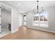 Open-concept dining area with hardwood floors, modern chandelier, large window, and adjacent half bathroom at 1306 Yates St, Denver, CO 80204