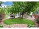 Landscaped backyard with a circular patio area and mature trees at 11056 W Rowland Ave, Littleton, CO 80127