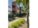 Modern brick townhome with metal accents, balcony, and landscaped walkway with yellow flowers at 85 Uinta Way # 405, Denver, CO 80230