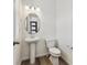 Bright powder room featuring a pedestal sink, oval mirror, and modern toilet at 24769 E 39Th Ave, Aurora, CO 80019