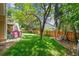 A large, well-maintained backyard features mature trees, a swing, and playhouse offering relaxation and play space at 1762 Red Fox Pl, Highlands Ranch, CO 80126