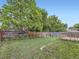 Large, grassy backyard featuring a wooden fence, mature trees, and a small deck at 6154 Quitman St, Arvada, CO 80003