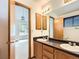 Bright bathroom featuring a double vanity, wood cabinets, and a view into the bedroom at 6154 Quitman St, Arvada, CO 80003