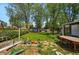 Spacious backyard featuring lush green grass, mature trees, and garden beds with a beautiful outdoor dining area at 5674 S Prescott St, Littleton, CO 80120