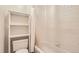 Bright bathroom with shower-tub combination, white tile, and convenient shelving beside the toilet at 4681 S Columbine Ct, Cherry Hills Village, CO 80113